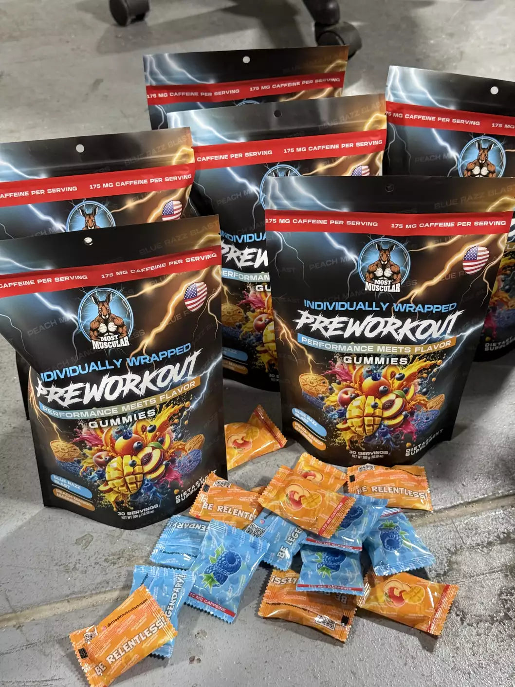 A pile of Most Muscular pre-workout gummies bags and individual packets in various flavors, showing the unique, single-serving design.